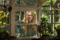 Femme regardant par la fenêtre de la cuisine — Photo de stock