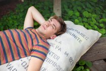 Young man lying on sack daydreaming — Stock Photo