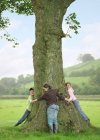 Niños abrazando el árbol en la granja - foto de stock