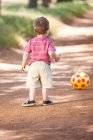 Хлопчик Тоддлер з м'ячем на брудній дорозі — стокове фото