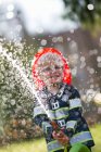 Garçon en costume de pompier jouer avec tuyau — Photo de stock