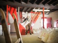 Worker emptying sack of grain in brewery — Stock Photo