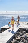 Eltern und zwei junge Mädchen gehen auf Seebrücke — Stockfoto