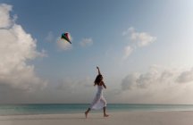 Mulher voando um papagaio na praia tropical — Fotografia de Stock