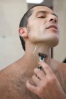 Мужчина бреется в ванной — стоковое фото