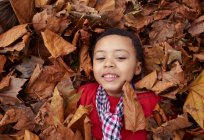 Girl playing in autumn leaves — Stock Photo