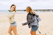 Girlfriends playing chasing game on the beach — Stock Photo