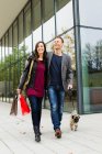 Paar spaziert mit Hund auf Stadtstraße — Stockfoto