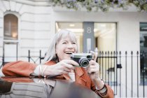 Mujer tomando fotos en la calle de la ciudad - foto de stock