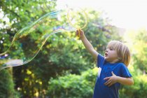 Мальчик делает огромный пузырь на заднем дворе — стоковое фото