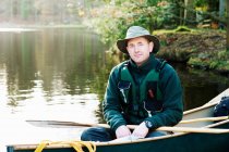 Uomo seduto in canoa sul lago ancora — Foto stock