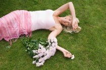 Relajada mujer acostada en la hierba - foto de stock