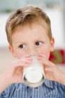 Jovem menino bebendo copo de leite — Fotografia de Stock
