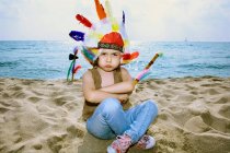 Niño en tocado indio en la playa - foto de stock