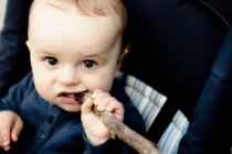 Baby chewing on wooden stick — Stock Photo