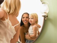 Mother and daughter looking at mirror. — Stock Photo