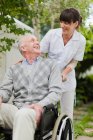 Nurse wheeling older patient outdoors — Stock Photo