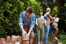 Four friends stacking terracotta plant pots — Stock Photo
