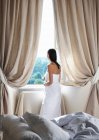 Woman standing by the window in towel — Stock Photo
