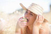 Жінка їсть яблуко у високій траві — стокове фото
