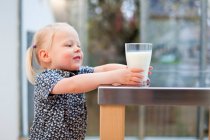 Toddler girl holding glass of milk — Stock Photo