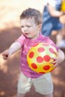 Малыш с мячом на грунтовой дороге — стоковое фото