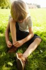Мальчик завязывает шнурки в траве — стоковое фото