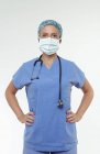 Chirurg mit Operationsmaske, die Hände auf den Hüften und Blick in die Kamera — Stockfoto