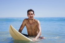 Homem sentado na prancha de surf na água — Fotografia de Stock