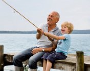 Boy fishing with grandfather at lake — Stock Photo