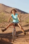 Femme à vélo dans un paysage désertique — Photo de stock