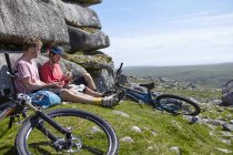 Велосипедисти, які сидять на скелястому вилові, мають пікнік — стокове фото