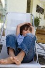 Boy relaxing in deck chair on patio — Stock Photo