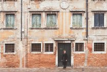 Mujer joven mirando por encima de su hombro desde la vieja puerta, Venecia, Italia - foto de stock