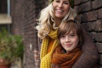 Mother and son smiling against brick wall, portrait — Stock Photo