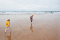 Bambini che giocano sulle onde sulla spiaggia — Foto stock