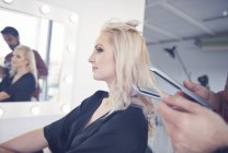 Mãos de cabeleireiro segurando alisadores de cabelo para modelo na sessão de fotos — Fotografia de Stock