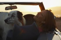 Woman laughing with dog in convertible — Stock Photo
