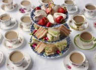 Vintage tea cups and sandwiches on cakestand prepared for afternoon tea — Stock Photo