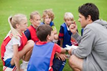 Entrenador hablando con los niños equipo de fútbol - foto de stock