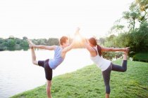 Couple practicing yoga by water — Stock Photo