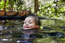 Крупним планом хлопчик плаває в річці в лісі — стокове фото