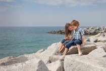 Children talking on rocks at beach — Stock Photo