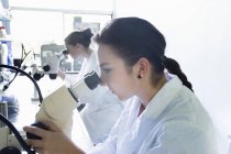 Biology students using microscopes — Stock Photo