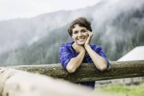 Porträt einer jungen Frau, die gegen Zaun gelehnt ist, tirol Österreich — Stockfoto