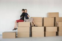 Businesswomen sitting on stack of cardboard boxes — Stock Photo