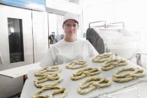 Baker holding baking sheet of pretzels — Stock Photo