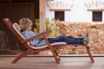 Boy using laptop in deck chair — Stock Photo