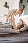 Metà donna adulta tenendo la figlia del bambino a letto — Foto stock