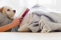 Frau liest im Bett mit Hund — Stockfoto